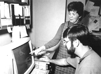 Photograph of scientists comparing fossil shapes on a computer screen